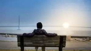 Das glücklichste Land der Welt leben die Menschen ein entspanntes Leben - ein Mann sitzt auf einer Parkbank und sieht sich den Sonnenaufgang an